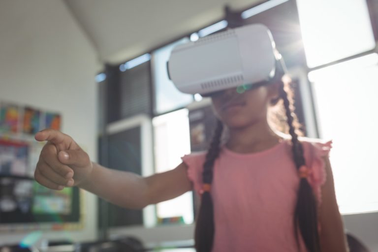 Girl wearing virtual reality simulator in classroom